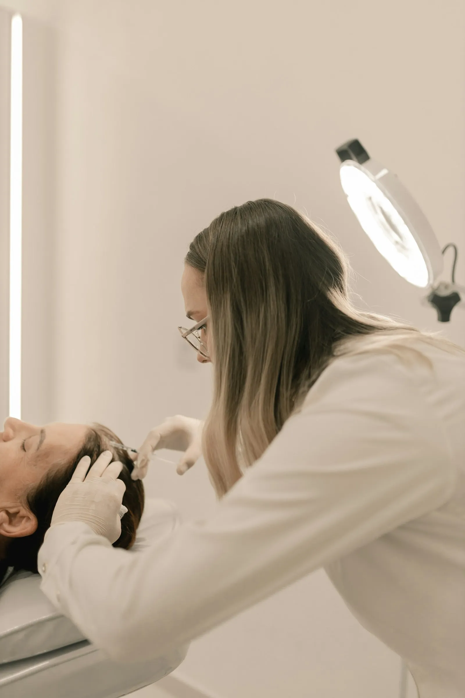Una esteticista revisa la piel de una clienta con una lámpara de aumento